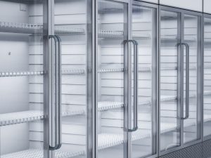 Empty commercial freezer not cooling due to possible malfunction, showing glass doors, metal shelves, and no stored products.