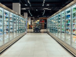 A supermarket aisle with commercial freezers stocked with frozen goods. Explore factors influencing commercial freezer repair costs and maintenance.