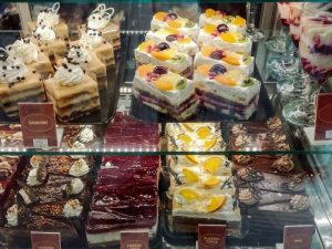 A poorly maintained cake display case shows sad-looking, slightly messy cakes. Poor cake display maintenance is evident.
