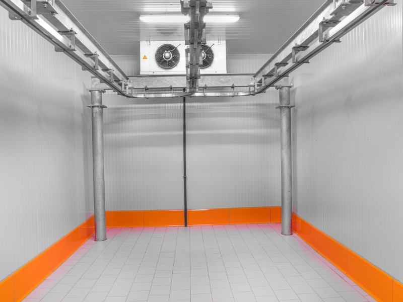 A spacious cool room requiring cool room maintenance, featuring a tiled floor, insulated walls, and ceiling-mounted refrigeration units.