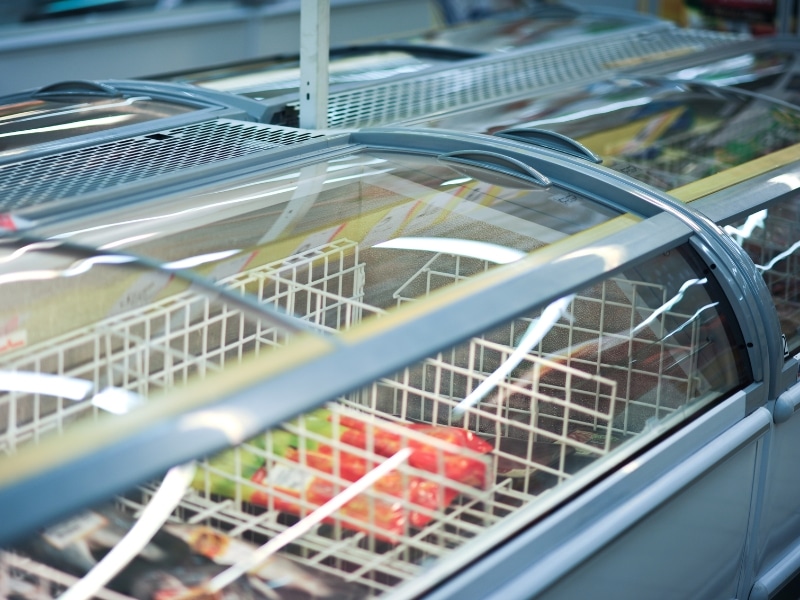 Chest freezers in supermarket aisle demonstrating commercial refrigeration repair cost factors.